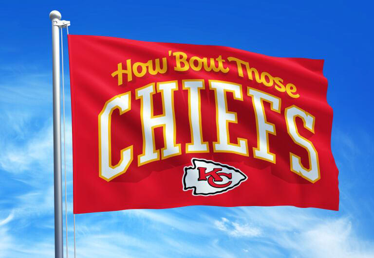 This year’s flag features Chiefs Head Coach Andy Reid’s famous catchphrase, “How ‘Bout Those Chiefs,” in white and gold lettering on a red background alongside the team’s official logo.