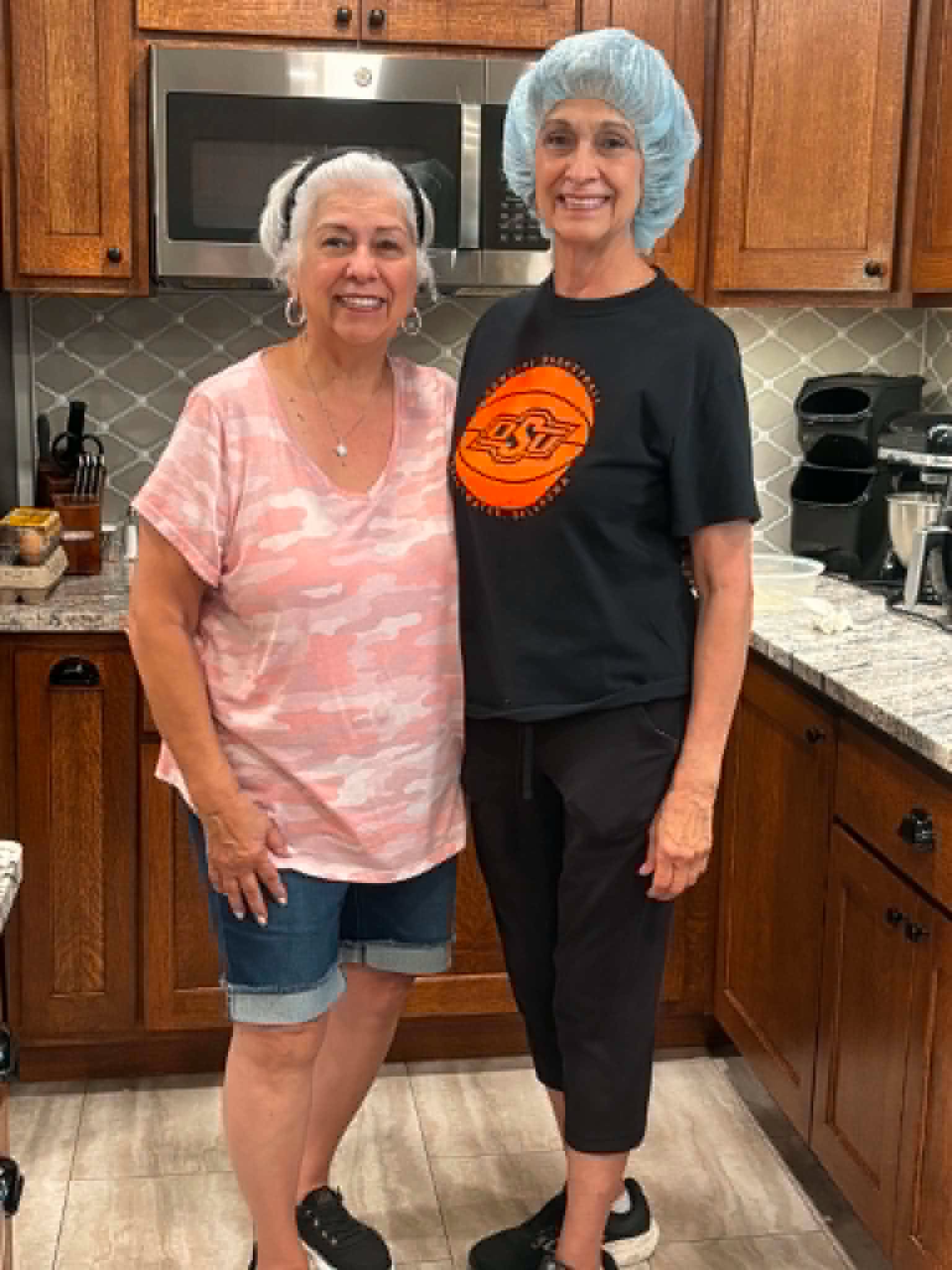 Two smiling female volunteers standing in a kitchen, ready to prepare a meal for families at the Ronald McDonald House.